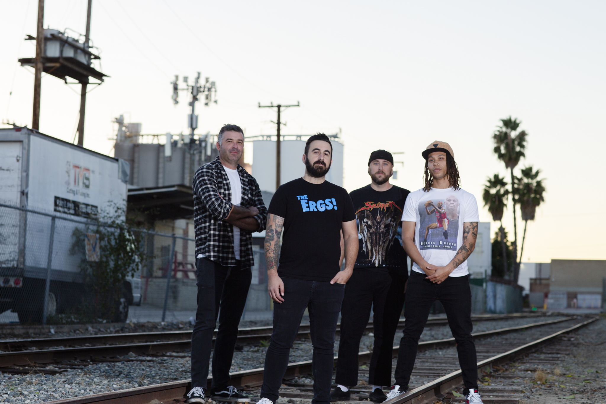 A photo of the punk rock band Stoke Signals taken in Vernon, California. The band is standing on railroad tracks. The photo was shot by Adam Stanzak.